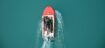 Top view of a red motorboat with fishermen navigating open turquoise waters.